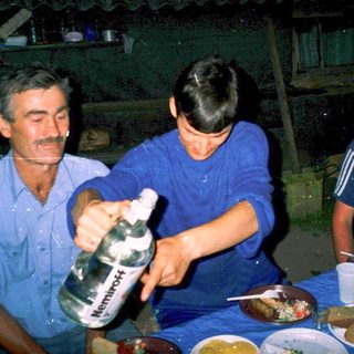Three men sharing a meal indoors with homemade food and drinks.