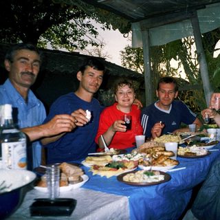 Group enjoying outdoor meal together under tent.