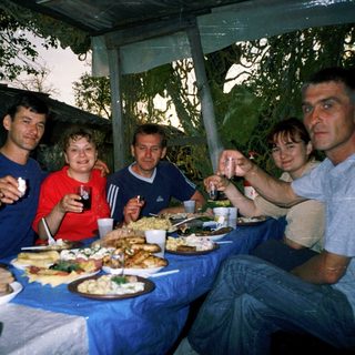 Group enjoying outdoor meal together under tent.