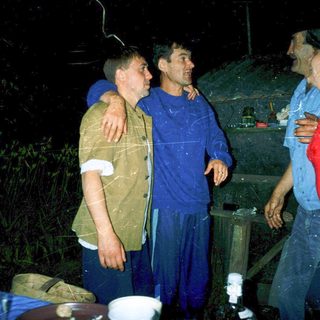 Three men standing indoors during heavy rain.