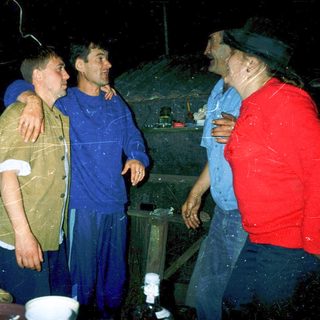Three men standing indoors during heavy rain.