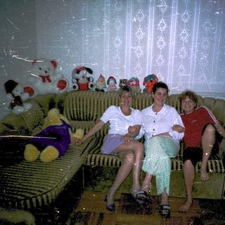 Three people posing indoors on a couch.