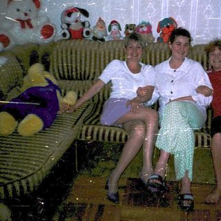 Three people posing indoors on a couch.