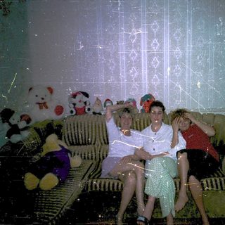 Family group photo with stuffed toys indoors.