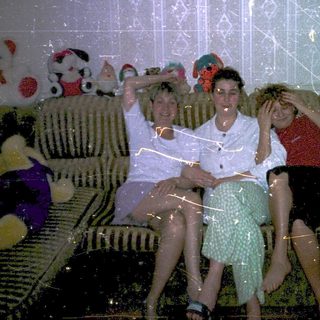 Family group photo with stuffed toys indoors.