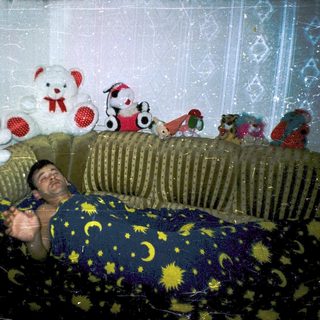 Man lying on bed with stuffed toys.