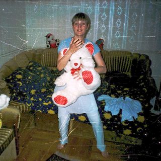 Child dressed in teddy bear costume holding plush bear.