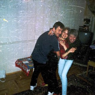 Three people hugging indoors during snowball fight.