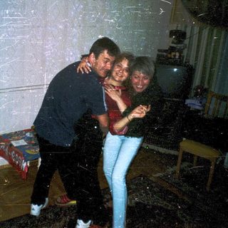 Three people hugging indoors during snowball fight.