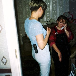 Two women in bathroom, one talking on phone.