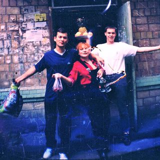 Three people posing outside a brick building.