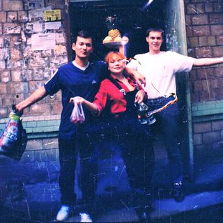 Three people posing outside a brick building.