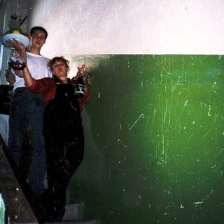 Two people standing on stairs holding drinks.