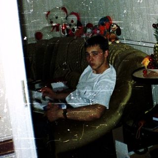 Man sitting indoors reading near a window.