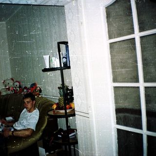 Man sitting indoors reading near a window.