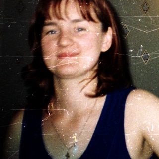 Woman standing in tiled shower with diamond-pattern wall.