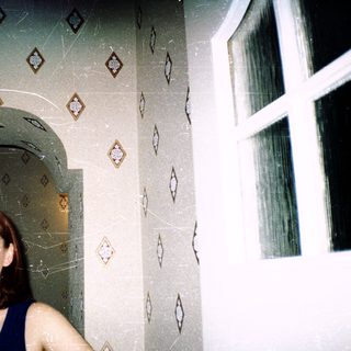 Woman standing in tiled shower with diamond-pattern wall.