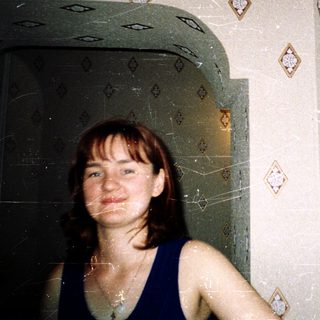Woman standing in tiled shower with diamond-pattern wall.