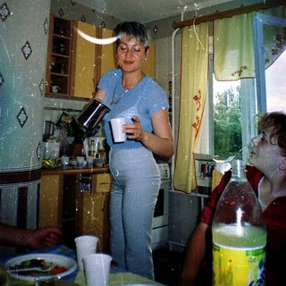 Woman pouring coffee in kitchen with child.