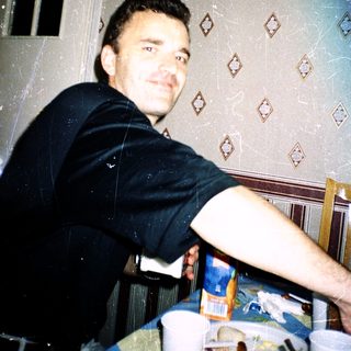 Man smiling indoors near kitchen counter.