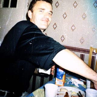 Man smiling indoors near kitchen counter.