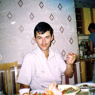 Young man eating indoors with retro patterned wall.