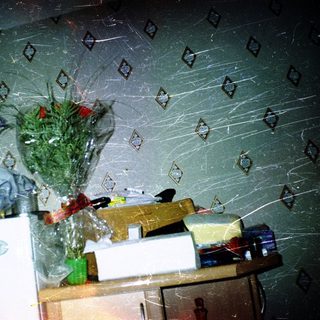 Cluttered room with spider webs, wrapped items, and a vase.