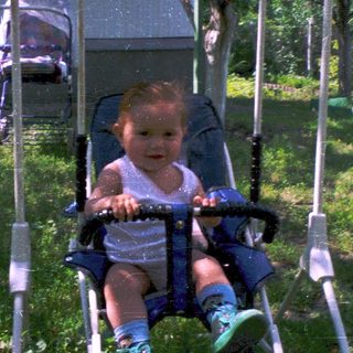 Baby riding a swing in backyard.
