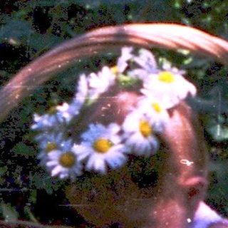 Child sitting in wicker basket surrounded by flowers.