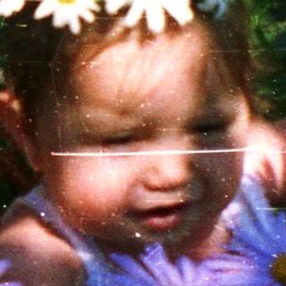 Child surrounded by flowers in woven basket.