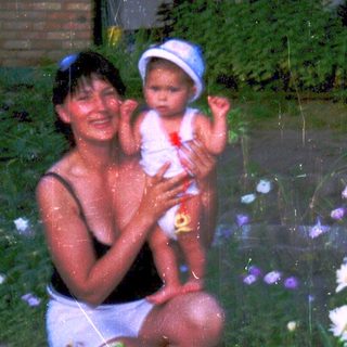 Woman and baby playing in shallow water surrounded by flowers.