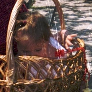Woman and child holding basket near house entrance.