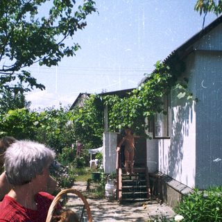 Woman and child holding basket near house entrance.
