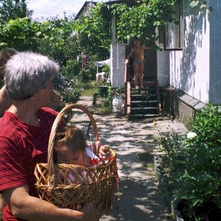 Woman and child holding basket near house entrance.