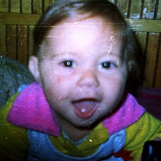 Young child with tongue out, blurred background.