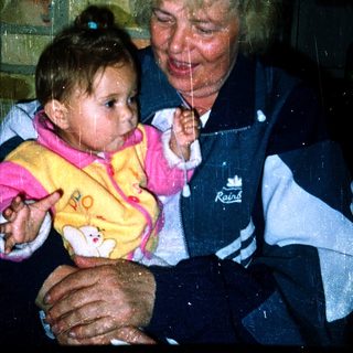 A woman holding a baby indoors during rain.