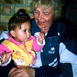 A woman holding a baby indoors during rain.