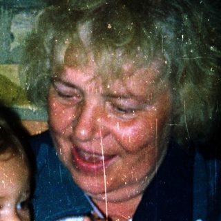A woman holding a baby indoors during rain.