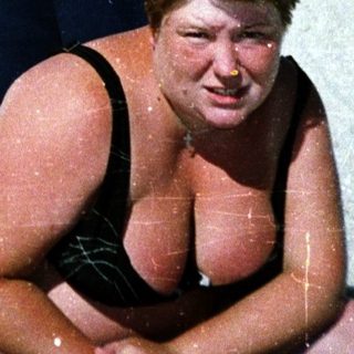 Person sitting on inflatable in sandy outdoor area.