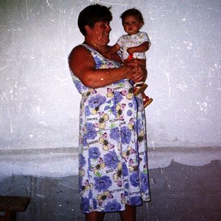 A woman holds a young child indoors.