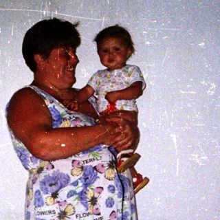 A woman holds a young child indoors.