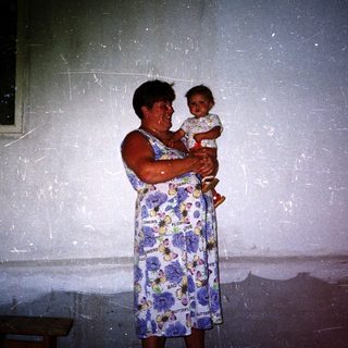 A woman holds a young child indoors.