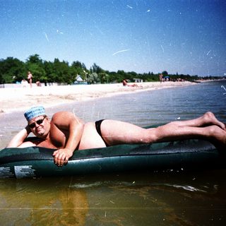 Man relaxing on inflatable raft at beach.