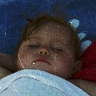 Baby sleeping peacefully in makeshift bed outdoors.