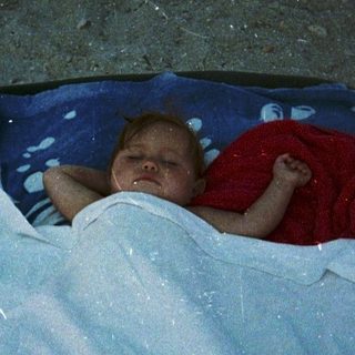 Baby sleeping peacefully in makeshift bed outdoors.