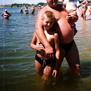 Family enjoying water at crowded beach.