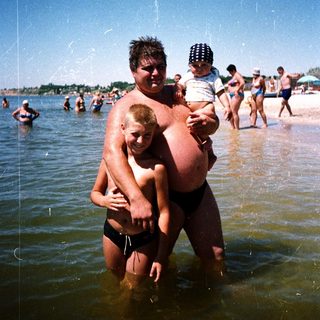 Family enjoying water at crowded beach.