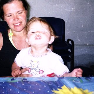Happy woman smiling with laughing toddler indoors.