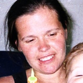 Happy woman smiling with laughing toddler indoors.