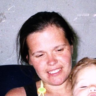 Happy woman smiling with laughing toddler indoors.